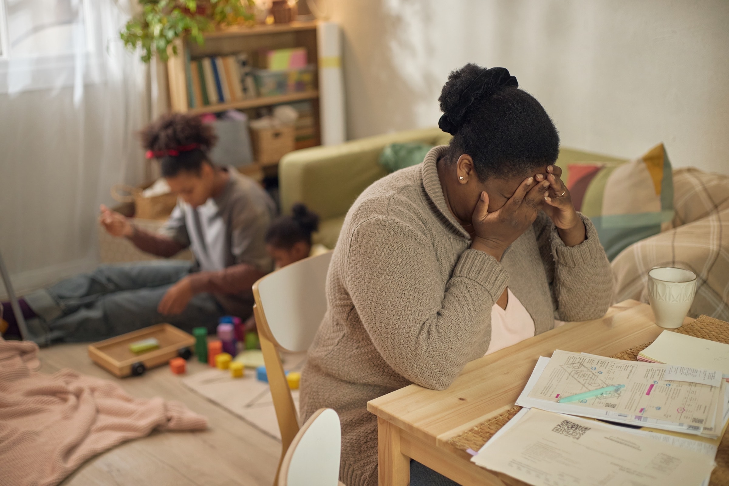 Parent overwhelmed by bills while children play nearby